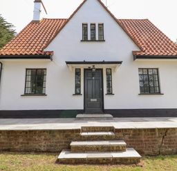 Front view of a house with a tiled roof black framed windows black door and brick steps at High Ground Reydon in Reydon