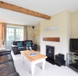 A living room with two leather sofas a wooden coffee table a fireplace and a television at Hoist Cottage Walberswick