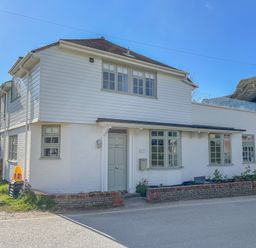A white two-story house with green windows and door beside a road at Sea Green Cottage Walberswick