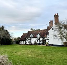 A large house with timber framing and multiple chimneys on a grass lawn with leafless trees at Church Farmhouse Cookley Near Halesworth