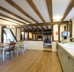 A kitchen and dining area with wooden beams and a wood floor at Church Farmhouse Cookley Near Halesworth