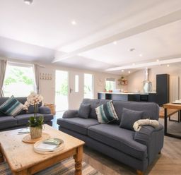 An open plan living room and kitchen with two blue sofas a wooden coffee table and a dining table at The Piglets in Newbourne Near Woodbridge