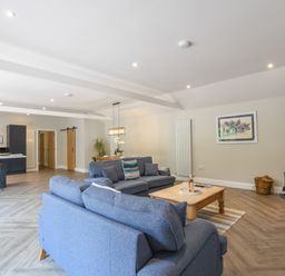 An open living room with blue sofas a wooden coffee table and a wood-burning stove at The Piglets in Newbourne Near Woodbridge