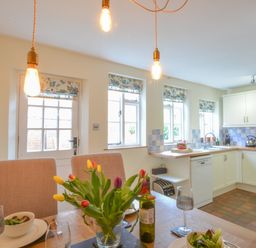 A kitchen with dining table flowers and tableware at Chapel Cottage Newbourne Near Woodbridge