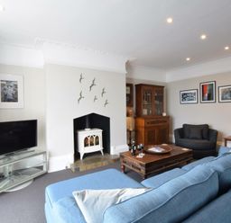 A living room with blue sofa wooden coffee table and television at Regatta Lookout in Aldeburgh