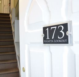 A stairway with carpet leading up and a white door with a sign showing 173 Regatta Lookout at Regatta Lookout in Aldeburgh