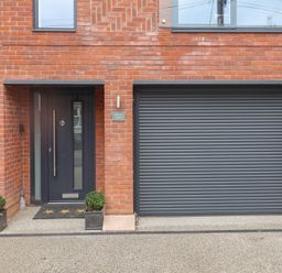 A front entrance with a door and garage door at Salt Marsh House, Southwold