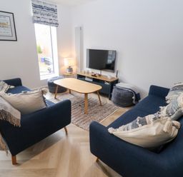 A living room with a sofa, coffee table, and television at Salt Marsh House, Southwold