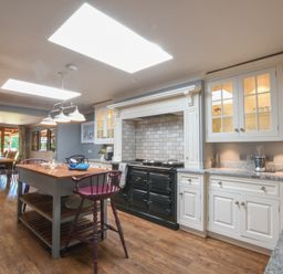 A kitchen with an island and dining table with chairs at Moat Barn in Hasketon Near Woodbridge