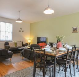 A dining table set with bowls and glasses next to a living room with sofas and a television at The Gallery, Blythburgh near Southwold