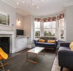 A living room with sofas a coffee table a fireplace and armchair at Kestrel in Southwold