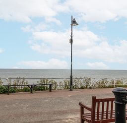 A coastal promenade with benches a lamppost a viewing telescope and a sea view at Dolphin Cottage Southwold