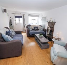 A living room with two brown sofas a light blue armchair a wooden floor and a coffee table at Dolphin Cottage Southwold