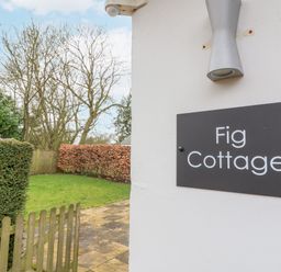 An outdoor sign for Fig Cottage with grass and hedges in the background at Fig Cottage, Pettistree