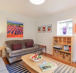A living room with a sofa, armchair, and bookshelf at Fig Cottage, Pettistree Near Woodbridge