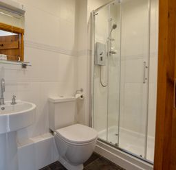 A bathroom with a sink a toilet and a shower with glass doors at Three Chantry Barns Orford