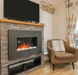 A chair with cushion next to a fireplace with a TV above and window with blinds and curtains at 8 Woodlands Water Yeat Coniston Water