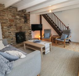 A living room with a fireplace and sofa at Candle Croft in Tolgus Mount near Redruth