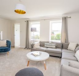 A living room with a gray sectional sofa a blue armchair and a round white coffee table at Bryntirion in Moelfre