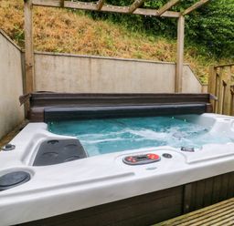 An outdoor hot tub with water jets and a control panel on a wooden deck area at Rose Cottage in Okehampton