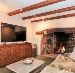 A living room with a fireplace and television at Rose Cottage in Okehampton