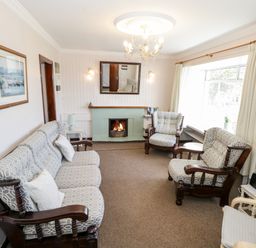 A living room with a sofa and armchairs around a fireplace at Sea Watch House in Roundstone County Galway