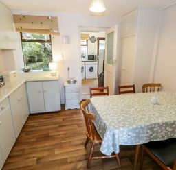 A kitchen with a dining table covered with a patterned tablecloth and wooden chairs at Sea Watch House in Roundstone County Galway