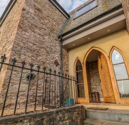 A stone building with a wooden arched door and narrow arched windows at The Old Chapel in Dittisham