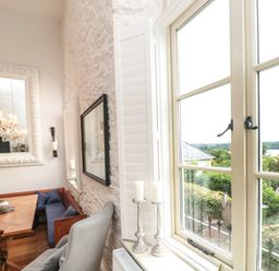 A dining area with a wooden table and cushioned bench near a window with candles at The Old Chapel in Dittisham