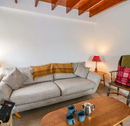 A living room with a sofa, table, and lamp at Ceunant near Newport