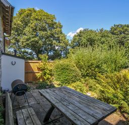A garden with a table, chairs, and barbecue at The Mews in Blisland