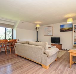 A living room with a sofa and dining area at The Mews in Blisland