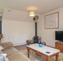 A living room with a television and wood stove at The Mews in Blisland