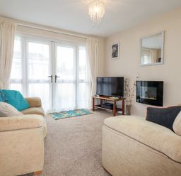 A living room with sofas a television and a wall-mounted fireplace at Smugglers in Liskeard near St Cleer