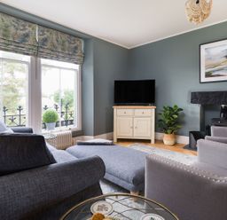 A living room with grey sofas a television on a cabinet and a fireplace at Wansfell at Lipwood House in Windermere