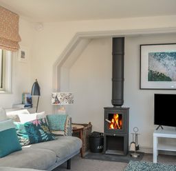 A living room with a wood stove and television at The Lookout in Polzeath