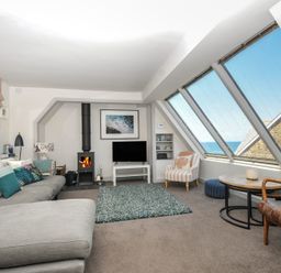 A living room with a sofa and television at The Lookout in Polzeath