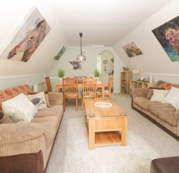 A living room with brown sofas a wooden coffee table and a dining table with chairs at 17 Valley Lodges in Gunnislake