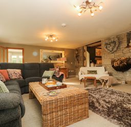 A living room with a gray sofa and a wicker coffee table near a fireplace at Lower Gadles Burnthouse near Falmouth