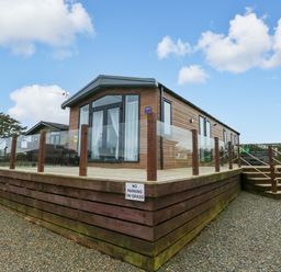 A holiday lodge with decking and steps at Oyster Lodge in Little Haven