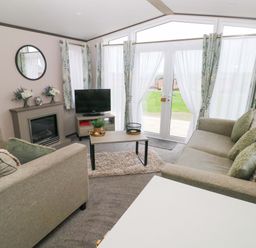 A living room with sofa and television at Oyster Lodge in Little Haven