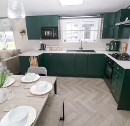 A kitchen with cabinets and dining table at Oyster Lodge Little Haven