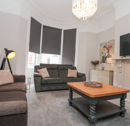 A living room with two sofas a wooden coffee table a fireplace and a television at Westbourne House in Scarborough