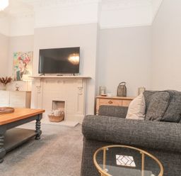 A living room with a television above a fireplace and a coffee table at Westbourne House in Scarborough