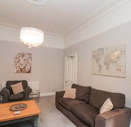 A living room with dark sofas a wooden coffee table and wall art at Westbourne House in Scarborough