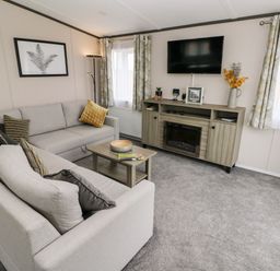 A living room with two sofas a coffee table a TV on the wall and a cabinet with a fireplace at Ramsey in Broad Haven
