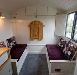 A narrow seating area with two benches and cushions with animal prints at Shepherds Hut in Dunvegan