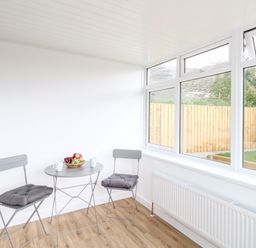 A small room with two gray chairs with cushions and a gray round table with mugs and a bowl of fruit at Cliff Barn in Burton Bradstock