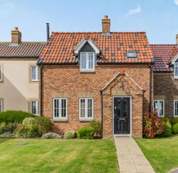 A brick house with a tiled roof a black front door and windows with white frames and a garden path at Lantern House in Filey