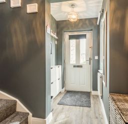 An entrance hallway with white front door stairs on the left and a wicker basket on the right at Lantern House in Filey
